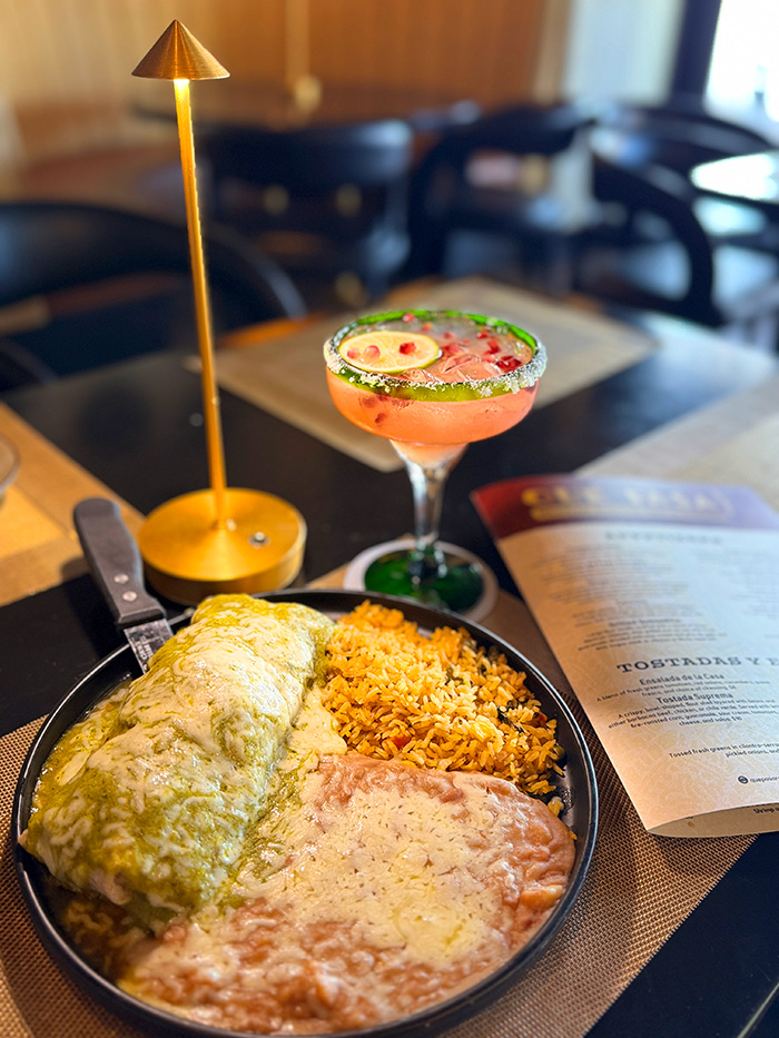 Wet-style burrito smothered in salsa verde and melted jack cheese with rice and beans