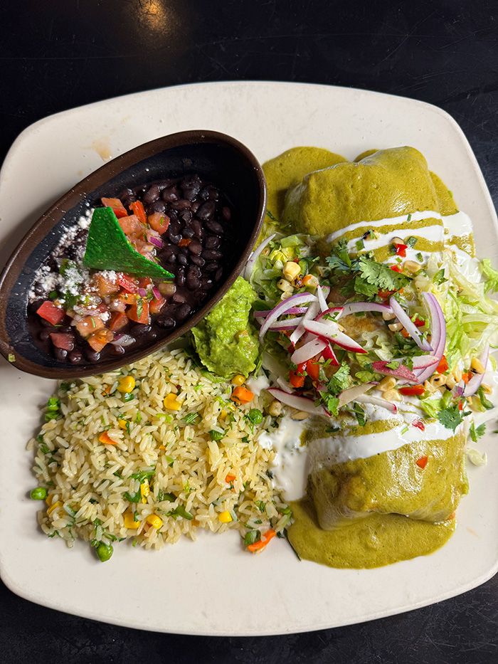 Gourmet burrito with mild tomatillo sauce and melted cheese, served with rice, beans, guacamole, and pico de gallo