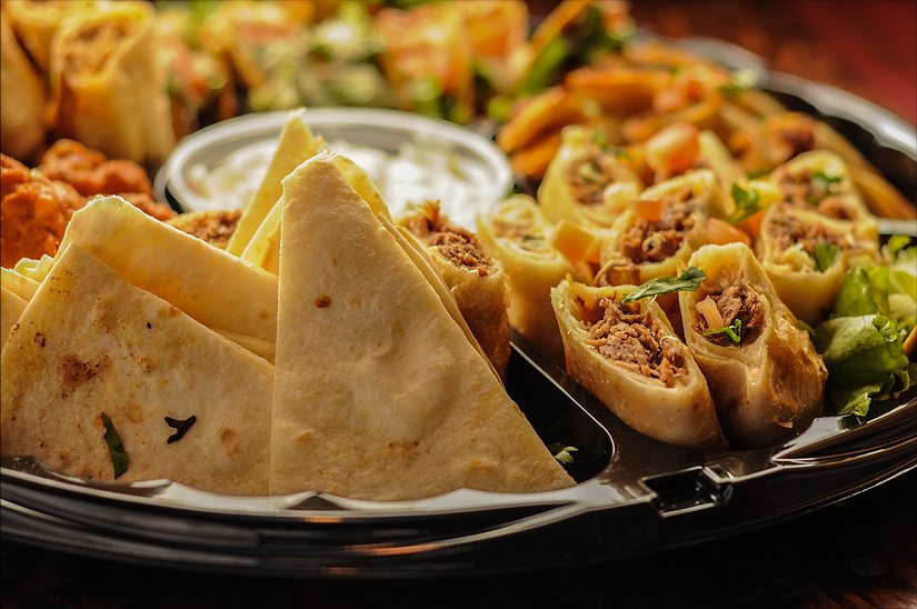 Close-up of Party Platter quesadilla wedges and mini chimis with sour cream