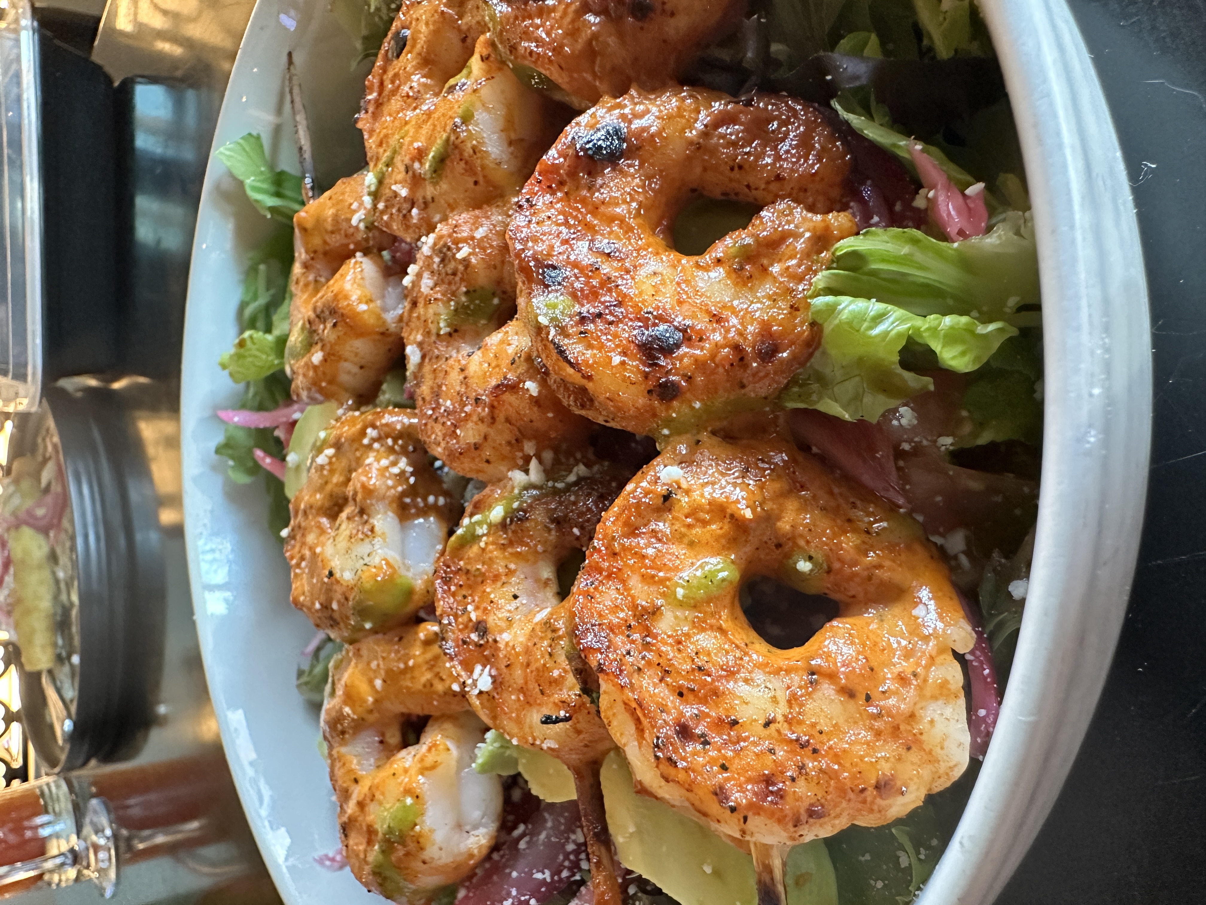 Chargrilled shrimp skewers piled over mixed greens with cotija cheese